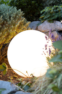LED Kugelleuchte weiß leuchtend im Blumenbeet zwischen Gartenpflanzen